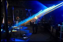 A darkly lit photo of a band performing on stage.