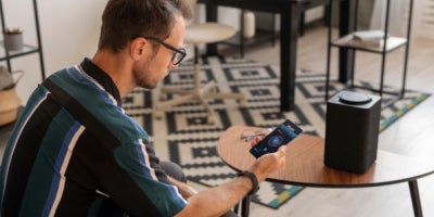 fiber internet vs fixed wireless, man holding phone next to speaker