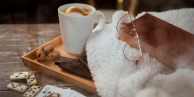 indoor activities for cold weather, cozy image with hot cocoa, a book, and cards