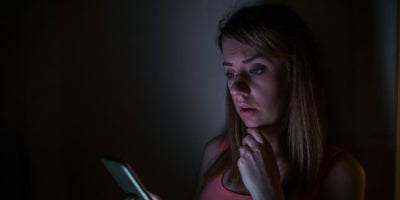 how to check for power outage, power outage near me, woman on phone in the dark