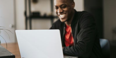 A man smiling while using a laptop connected to high-speed WiFi