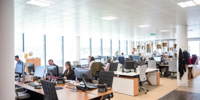 Interior of a big company with employees working hard at desks with computers