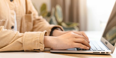 Close-up of individual typing on laptop.