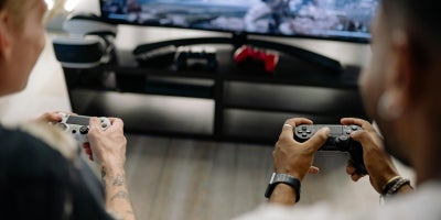 Two gamers hold controllers, playing couch co-op
