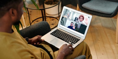 Man sitting in chair using video chat on laptop