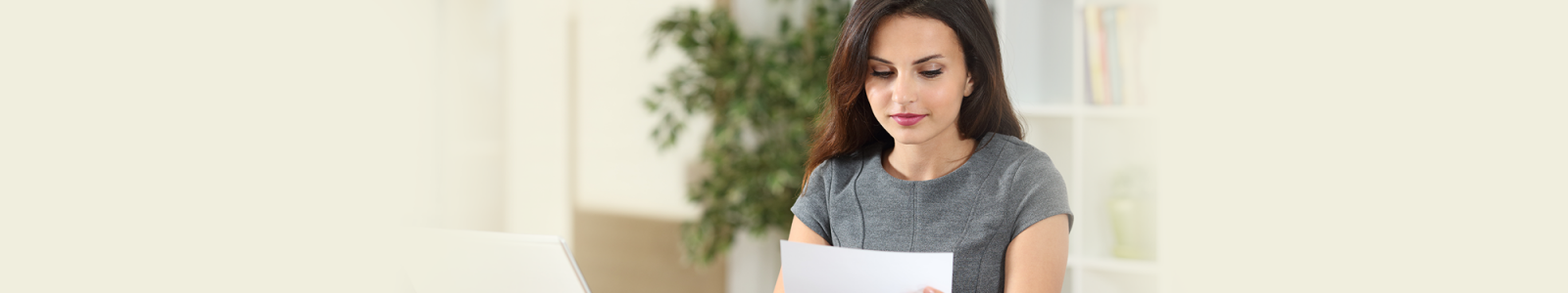 A woman sitting at a table reviewing her bill.