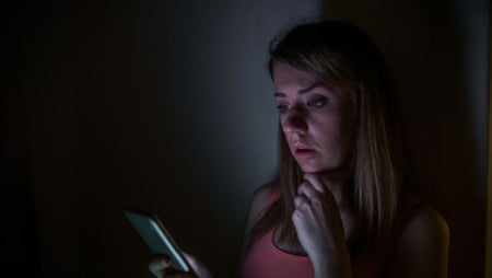 how to check for power outage, power outage near me, woman on phone in the dark