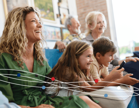 Family laughing on couch while watching tv
