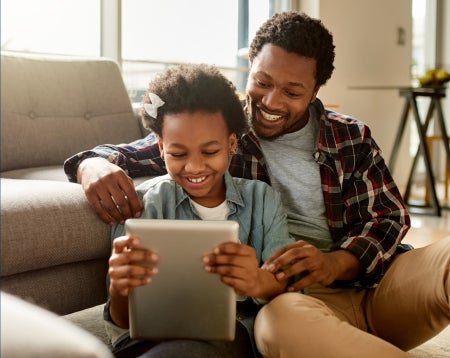 smiling father and daughter looking at a tablet