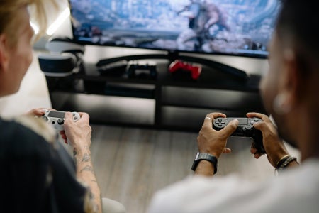 Two gamers hold controllers, playing couch co-op
