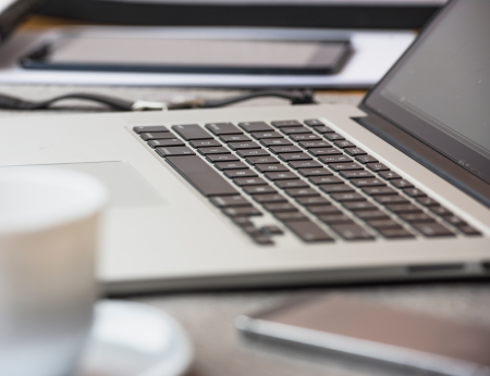 close up view of an laptop keyboard and a cup of coffee on a desk