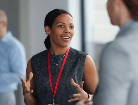 Woman wearing a red lanyard talking to other people