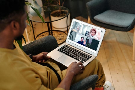 Man sitting in chair using video chat on laptop