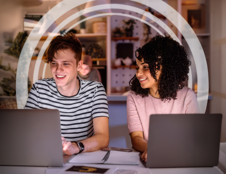 smiling college students with laptops sitting at desk