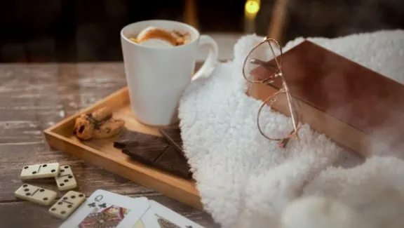 indoor activities for cold weather, cozy image with hot cocoa, a book, and cards