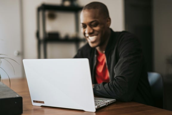 A man smiling while using a laptop connected to high-speed WiFi