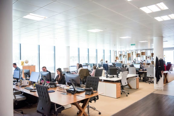 Interior of a big company with employees working hard at desks with computers