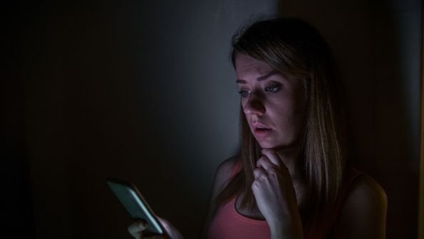 how to check for power outage, power outage near me, woman on phone in the dark