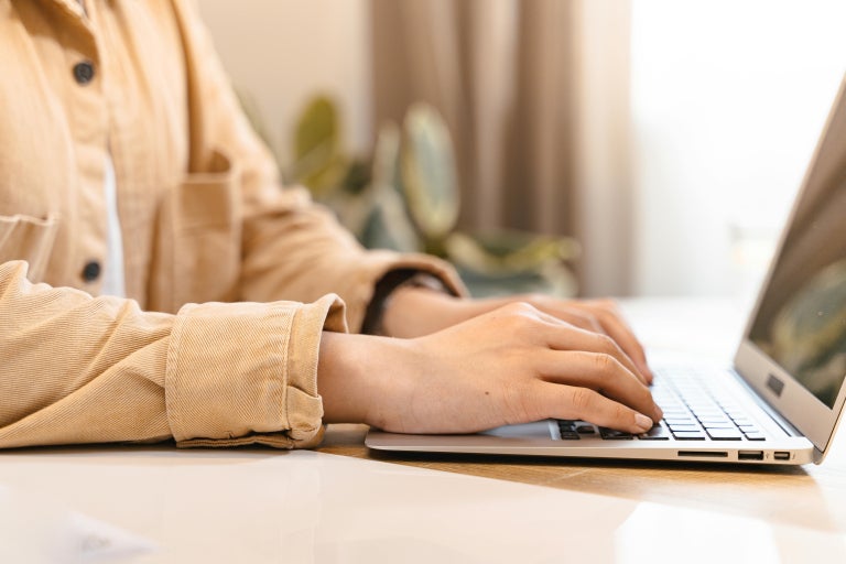 Close-up of individual typing on laptop.