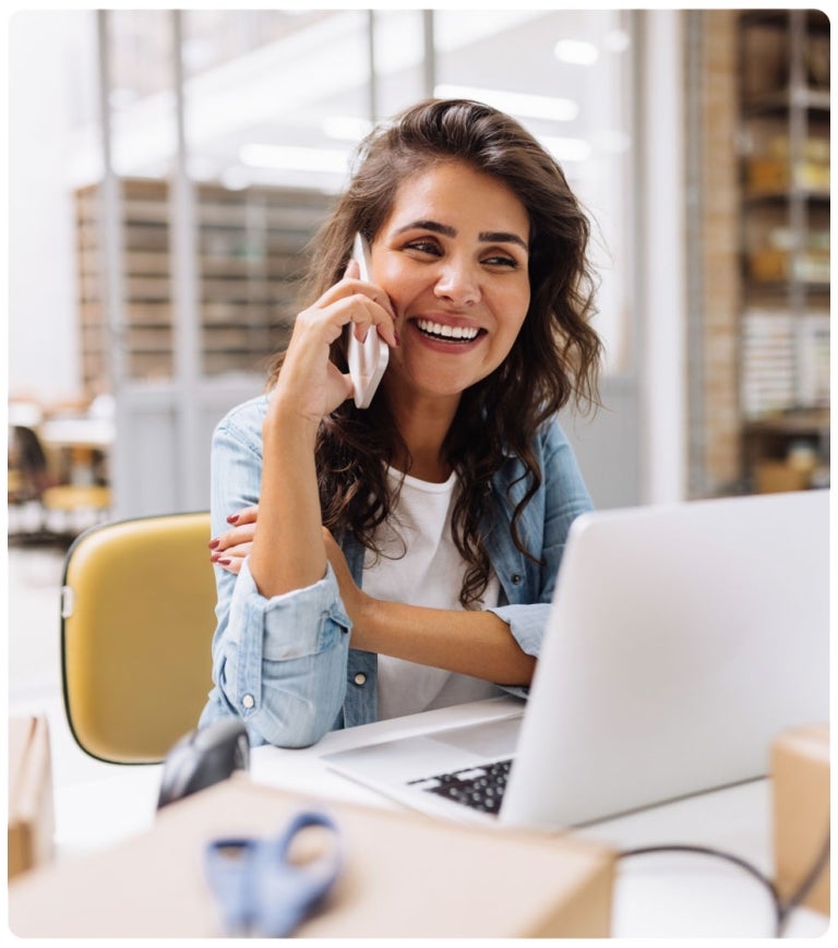 woman on mobile phone sitting at laptop