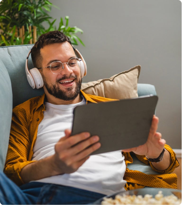 smiling man with glasses and headphones holding a tablet