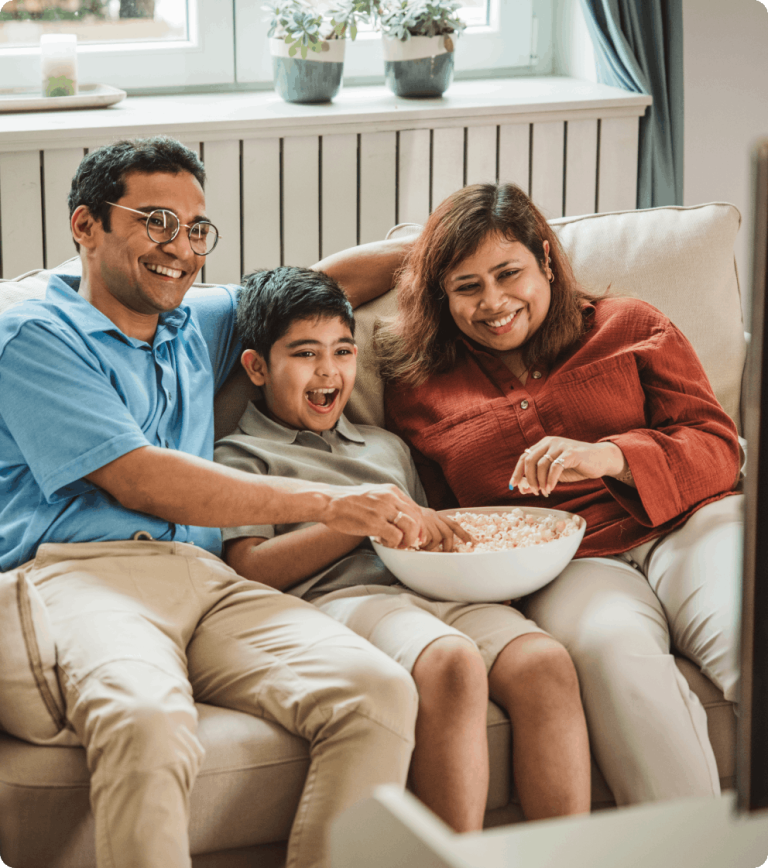 Family sitting on couch, eating popcorn and laughing